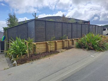 Small retaining wall with pine slatted fence.